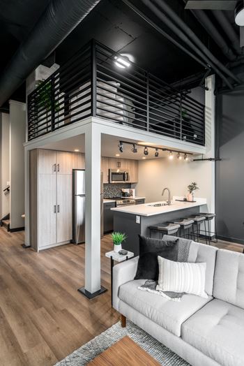 A modern kitchen with a white couch and wooden floors.